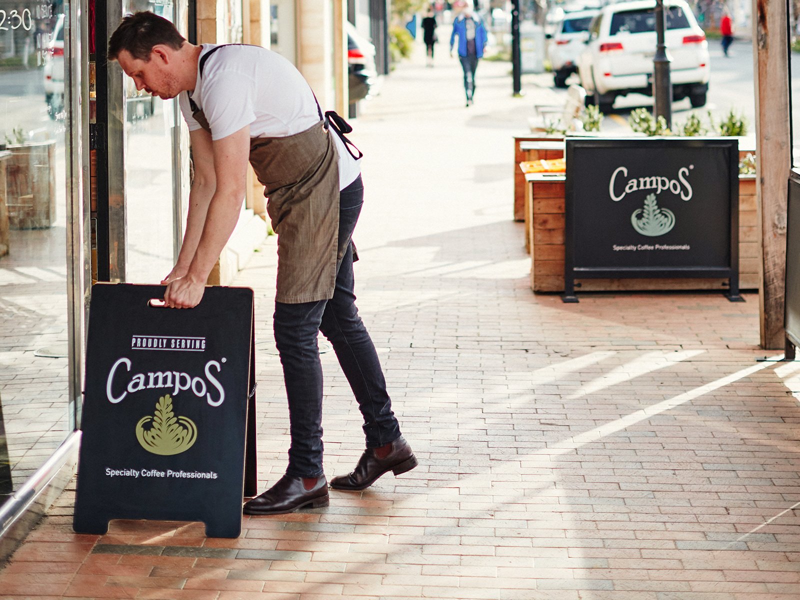 man with campos coffee sign